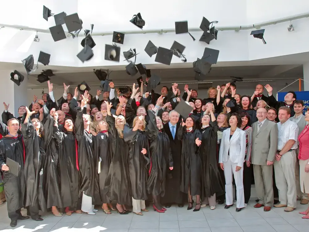 MBA graduates seated in academic regalia at a large graduation ceremony hall