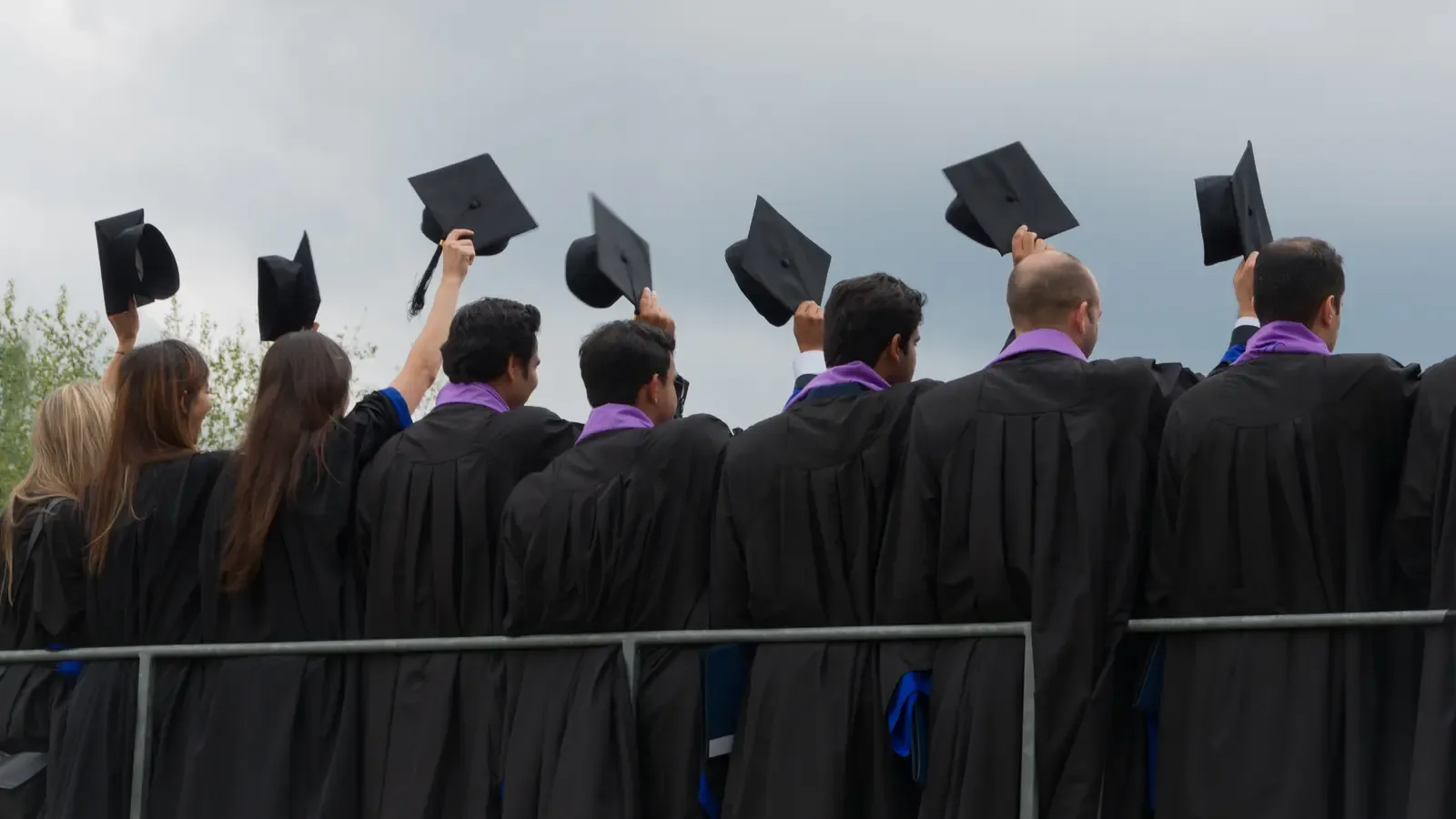 MBA graduates in caps and gowns celebrating outdoors on a European university campus